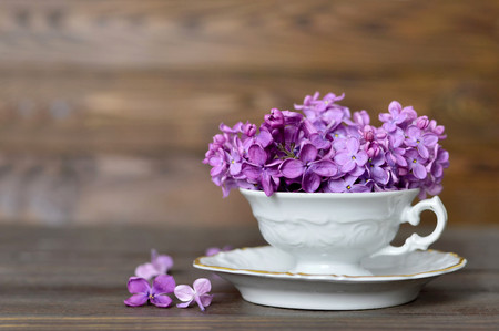 Flowers in the vintage cup on wooden background