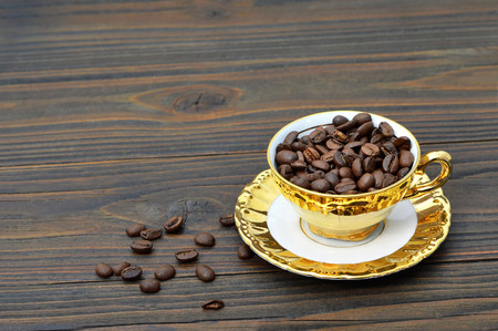 Coffee beans in the golden vintage cup on wooden backgroundの写真素材