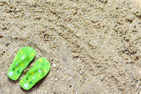 Summer background with flip flops on the sandy beachの写真素材