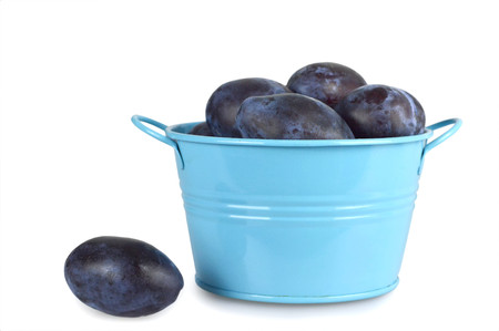 Plums in the bowl isolated on white backgroundの写真素材