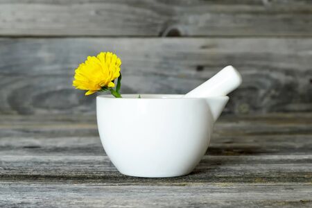 Calendula flower in a mortar on wooden backgroundの写真素材