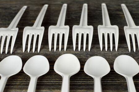 Plastic cutlery on wooden background. Disposable plastic forks and spoons