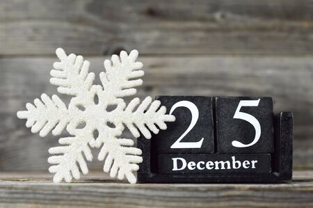 Wooden retro calendar with the date of Christmas and Christmas snowflake ornament