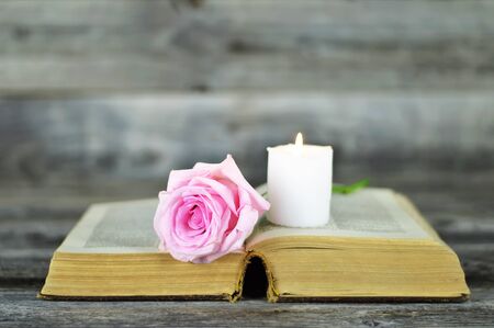 Sympathy card with burning candle and rose on open bookの写真素材