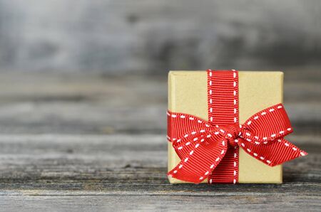 Gift box with red ribbon on wooden background with copy space