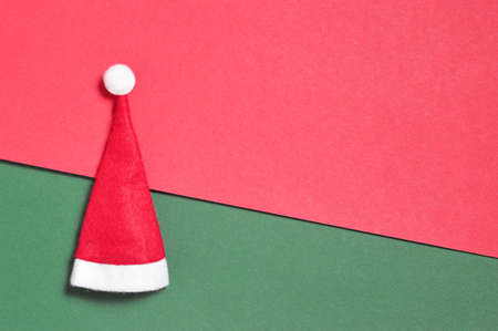 Christmas card with Santa hat on red and green paper background with copy spaceの写真素材