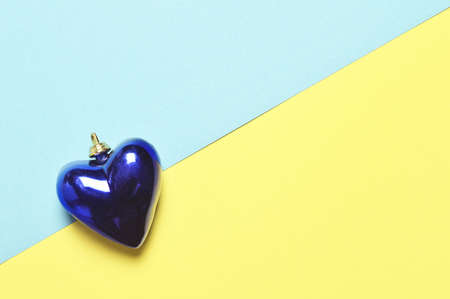 Christmas heart decoration on yellow and blue paper backgroundの写真素材