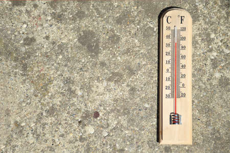 Thermometer on concrete background showing high summer temperatureの写真素材