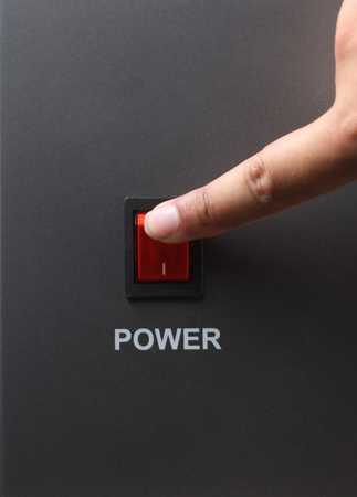 Asian male hand turning off red power switchの写真素材