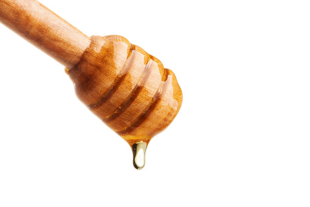 Honey dripping from a wooden honey dipper on isolate white background. ready to use with clipping path.の写真素材