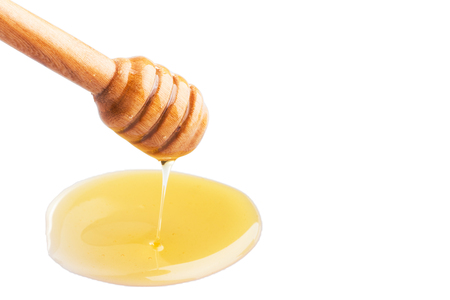 Honey dripping from a wooden honey dipper on isolate white background. ready to use with clipping path.の写真素材