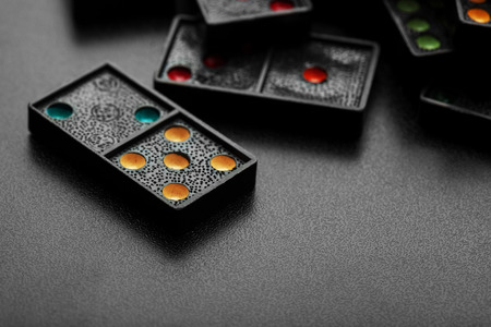 Black color dominoes with colorful dot game pieces lying on dark backgroundの写真素材