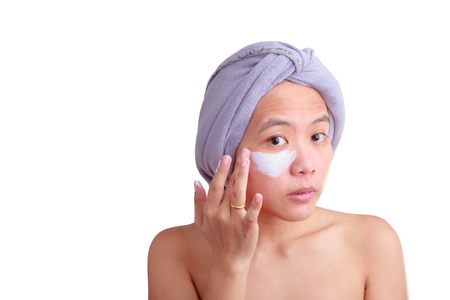 Beauty skin care cosmetics and health concept. Closeup Asian young woman applying cream on her face isolated on white color background with clipping path.の写真素材