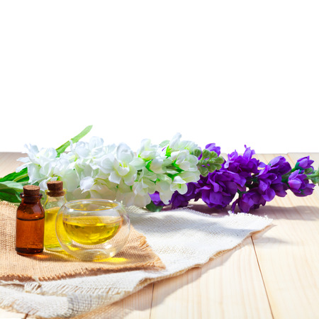 bottle of aroma essential oil or spa and natural fragrance oil with flower on wooden table isolated white background with clipping pathの写真素材