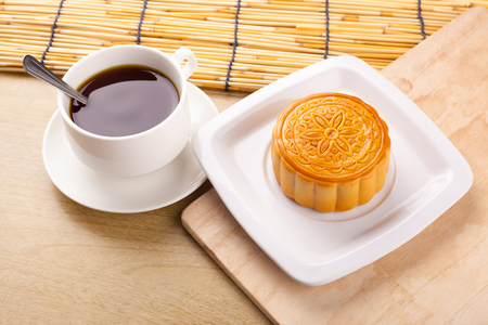 Chinese mid autumn festival foods. Traditional moon cakes on table setting with teacup.の写真素材