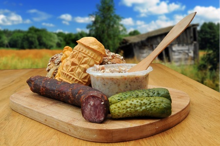 Bread, smoked cheese, kielbasa and other traditional food served outside in the countrysideの写真素材