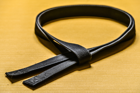 Martial art black belt isolated on yellow mat backgroundの写真素材