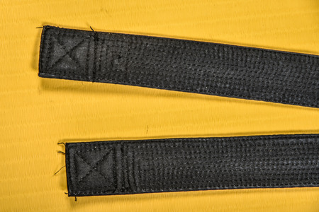 Martial art black belt isolated on yellow mat backgroundの写真素材