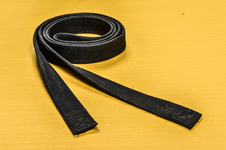 Martial art black belt isolated on yellow mat backgroundの写真素材