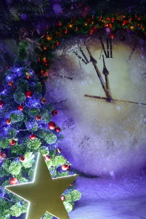 Christmas tree illuminated by a large luminous star on the background of a huge Christmas clockの写真素材
