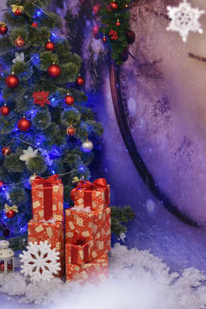 Christmas gifts under the tree against the background of a huge clock in the Studioの写真素材