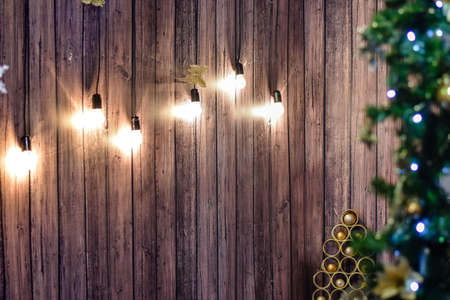 designer Christmas tree with toys on a brown wooden background on which glow incandescent lamps.の写真素材