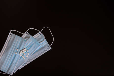 Protection face masks and Medical pills white on black background. Place for an inscription. Top view.の写真素材