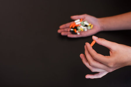 Colorful pills and medicines in the handson black background.. Place for an inscription.