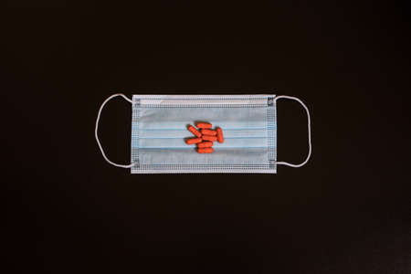 Protection face mask and medical pills red on black background. Top view.の写真素材