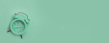 Green alarm clock on a green background. The view from the top. Banner. Place for the label.の写真素材