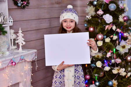 A girl in a Santa Claus helper costume. The girl holding blank piece of paper and pointing to copy space.の写真素材