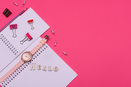Pink work desk with blank notebook and office supplies. Top view with copy space. Lettering Hello. Flat lay style.の写真素材