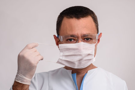 Professional doctor putting on protective face mask.