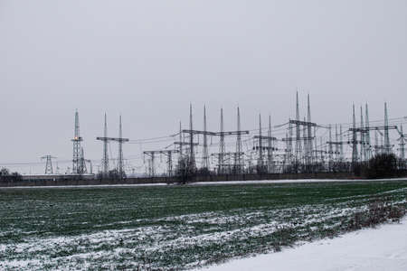 Electric substation on the background of a green field with winter wheat and snow in winter.の写真素材