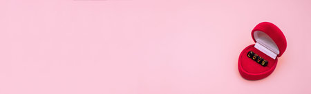 In a red gift box, love. The word love is laid out in letters on cubes. Banner on a pink background.