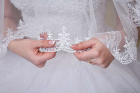 The bride holds a veil in her hands. A bride in a wedding dress.の写真素材