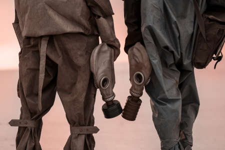 Two people with gas masks and chemical protection suits on the background of the scorched dead earth.の写真素材