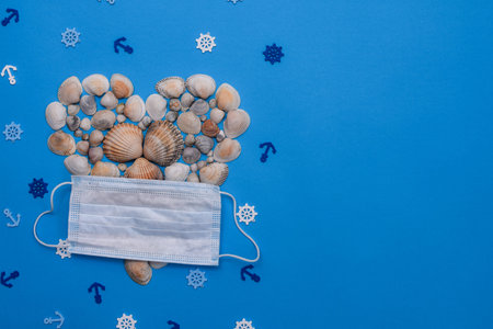 Seashells in the shape of a heart and a medical mask. Marine symbols. On a blue background....