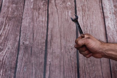 Wrench in hand. the oily, dirty working hands are clenched into a fist with a spanner. empty space