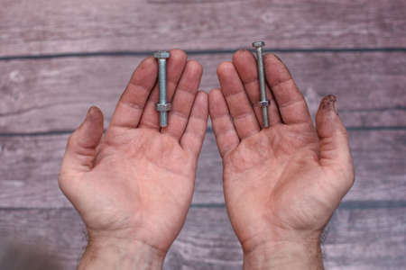 two bolts and nuts in working mens hands.の写真素材