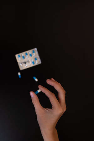 The girl holds the pill with her fingers in close-up.の写真素材