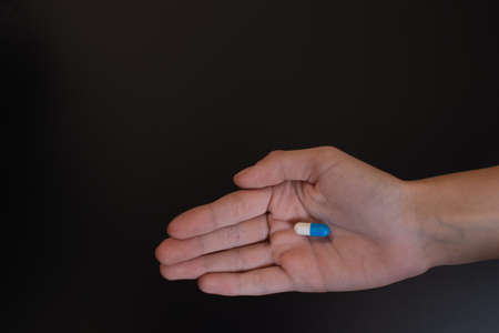 A pill capsule in the hand of a teenage girl.の写真素材