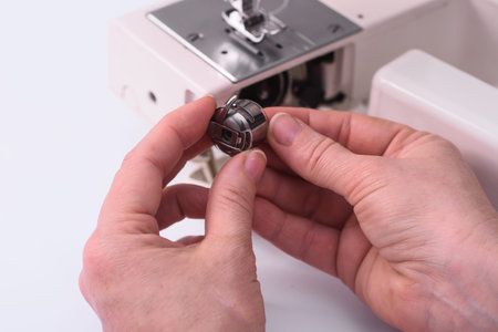 The tailors hands hold the spool of thread