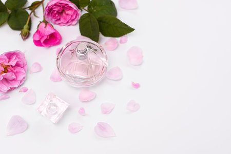 womens perfume in a glass bottle with pink flowers on a white background. empty space. Flat lay