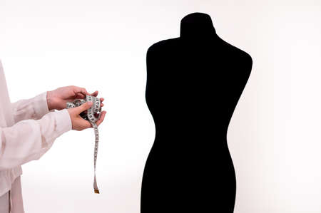 the seamstresss hands with a measuring ruler next to the mannequin.の写真素材