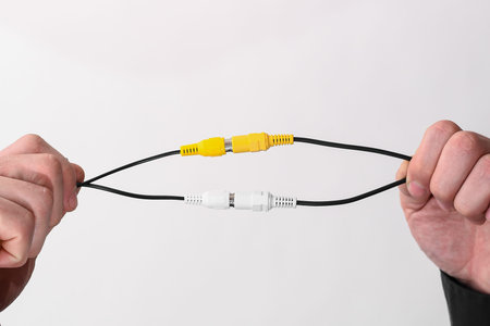 the wires connected by an RCA jack are white and yellow in male hands. copyspace