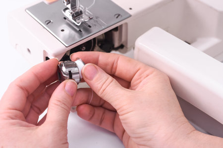 The seamstress inserts the spool into the bobbin of the sewing machine.