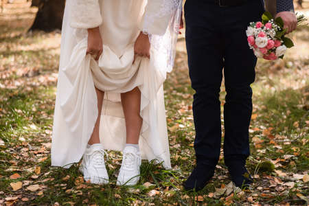 the bride lifted her skirt, showing white sneakers.の写真素材