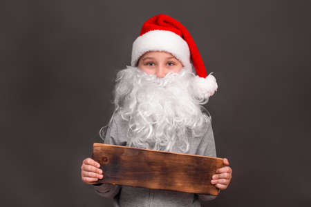 a boy 8-10 years old in a hat and with a Santa beard. mock upの写真素材