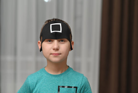 black mask with a white square on the boy is head.